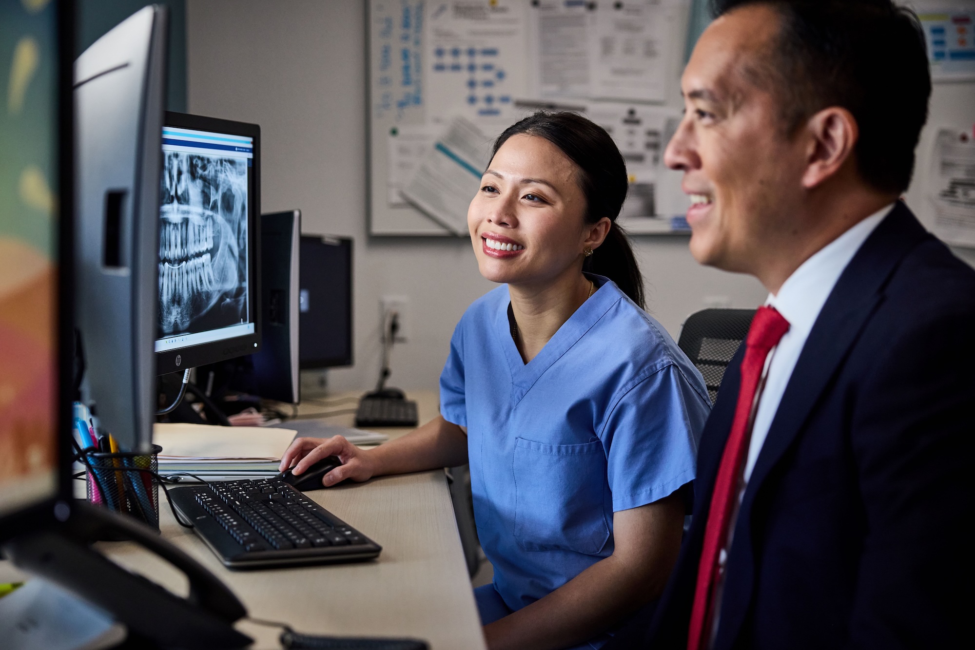 Two dentists looking at x-rays on a computer monitor
