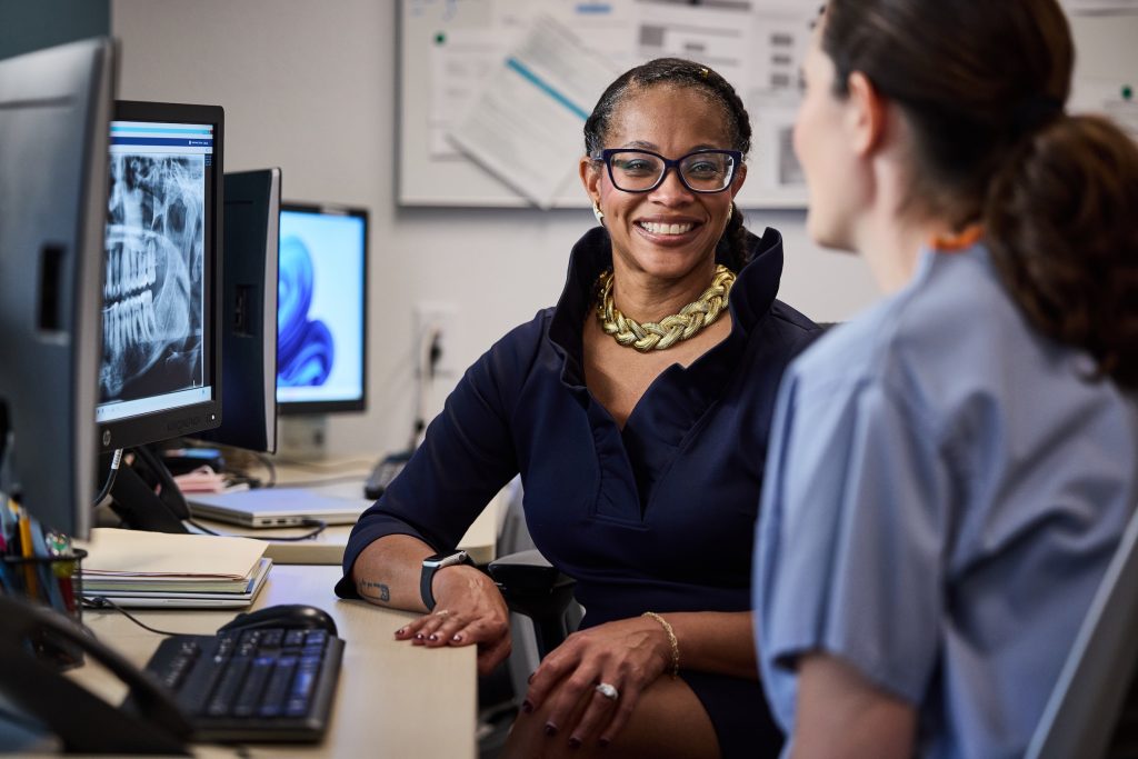 Two doctors smiling with x-rays in the background